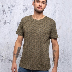 May include: A green t-shirt with a repeating pattern of small, stylized clover shapes. The shirt has a crew neck and short sleeves.