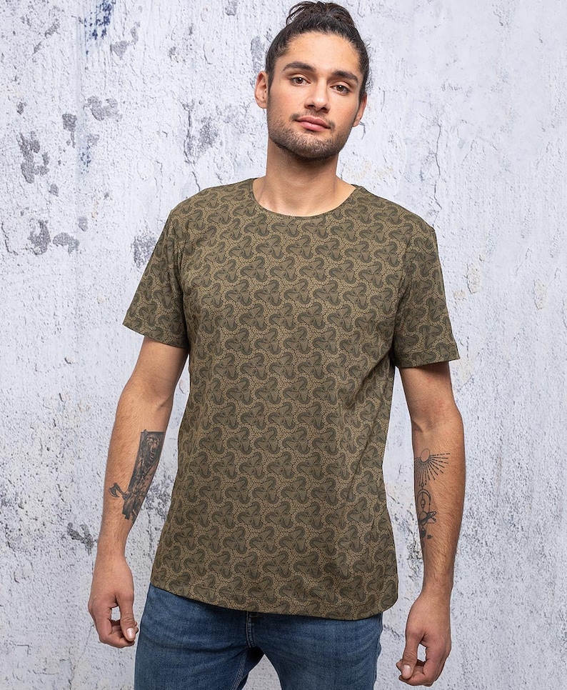 May include: A green t-shirt with a repeating pattern of small, stylized clover shapes. The shirt has a crew neck and short sleeves.