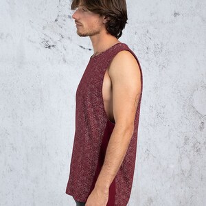 Puede incluir: Una camiseta sin mangas de color burdeos con un dise&ntilde;o estampado en blanco. La camiseta tiene un escote redondo y un corte holgado.