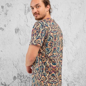 K&ouml;nnte beinhalten: Ein T-Shirt mit kurzen &Auml;rmeln und einem farbenfrohen, abstrakten Druck mit wirbelnden Mustern und Augen. Der Druck ist in Blaut&ouml;nen, Gelb, Orange und Braun.