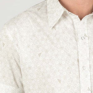 May include: White short-sleeved button-down shirt with a geometric pattern of hexagons and bees.