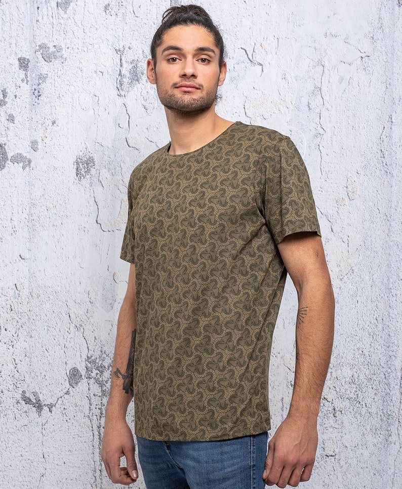 May include: A green short-sleeved t-shirt with a repeating pattern of small clover shapes.
