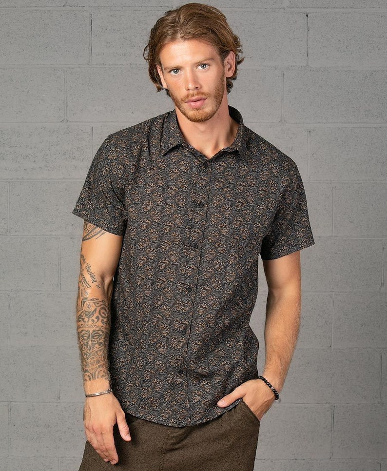 May include: A short-sleeved button-down shirt with a brown and black abstract print. The shirt has a collared neckline and a relaxed fit.