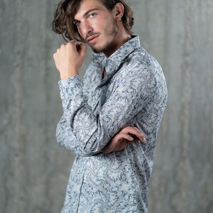 May include: A white long-sleeved shirt with a blue and white patterned design. The shirt has a button-down collar and a relaxed fit.