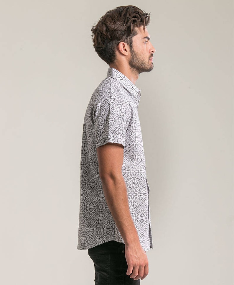 May include: A white short-sleeved button-down shirt with a black and white geometric pattern.