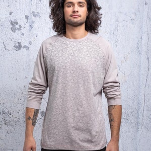 May include: A long-sleeved shirt with a geometric pattern in a light gray color. The shirt has a raglan sleeve design.