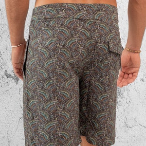 May include: Brown swim trunks with a paisley pattern. The trunks have a drawstring waist and a side pocket.