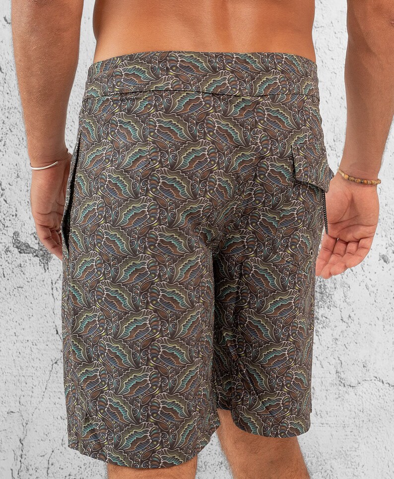 May include: Brown swim trunks with a paisley pattern. The trunks have a drawstring waist and a side pocket.