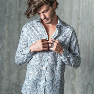 May include: A white long-sleeved shirt with a blue and white patterned design. The shirt has a button-down collar and a button-up front.