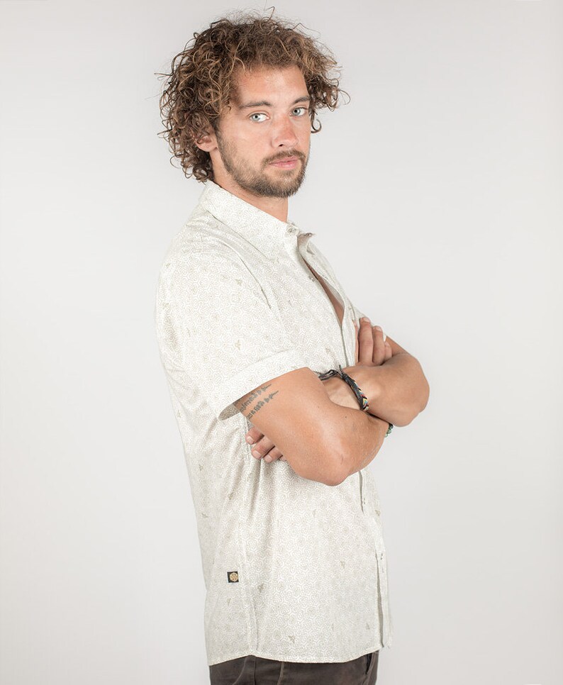 May include: A white short-sleeved button-down shirt with a small, all-over print. The shirt has a relaxed fit and a collar.