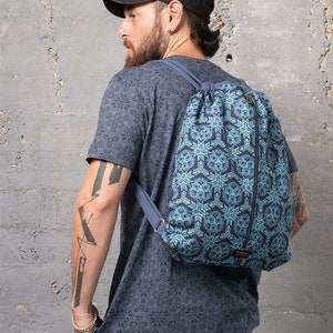 Puede incluir: Una mochila azul de cord&oacute;n con un patr&oacute;n geom&eacute;trico. La mochila tiene una cremallera en el lateral y una peque&ntilde;a etiqueta con la palabra "Cinch" en la parte inferior.
