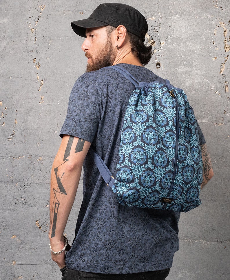 Puede incluir: Una mochila azul de cord&oacute;n con un patr&oacute;n geom&eacute;trico. La mochila tiene una cremallera en el lateral y una peque&ntilde;a etiqueta con la palabra "Cinch" en la parte inferior.