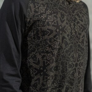May include: Black long-sleeve shirt with a geometric pattern in a lighter shade of gray. The shirt has a raglan sleeve design.