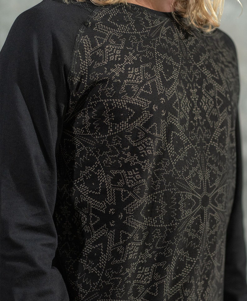 May include: Black long-sleeve shirt with a geometric pattern in a lighter shade of gray. The shirt has a raglan sleeve design.