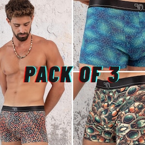 Puede incluir: Un pack de tres bóxers con diferentes estampados. Un par presenta un diseño geométrico rojo y negro, otro un patrón azul y verde, y el tercero un diseño marrón y verde. La cintura es negra con un logotipo.