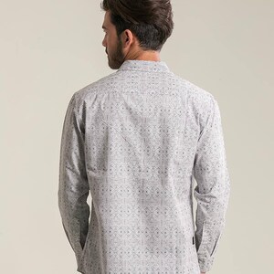 May include: A white long-sleeve shirt with a black geometric pattern. The shirt has a button-up collar and a relaxed fit.