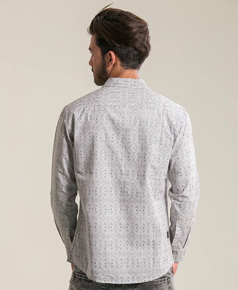May include: A white long-sleeve shirt with a black geometric pattern. The shirt has a button-up collar and a relaxed fit.
