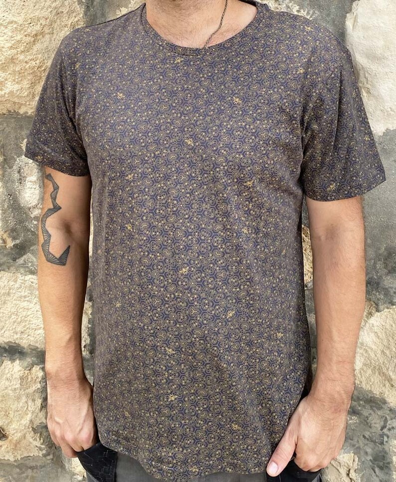 Puede incluir: Una camiseta gris oscura con un patr&oacute;n geom&eacute;trico dorado.