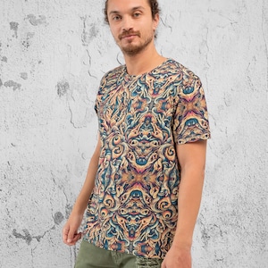 K&ouml;nnte beinhalten: Ein T-Shirt mit kurzen &Auml;rmeln und einem farbenfrohen, komplizierten Muster aus wirbelnden Linien und Formen. Das Muster erinnert an ein Kaleidoskop oder ein Mandala.