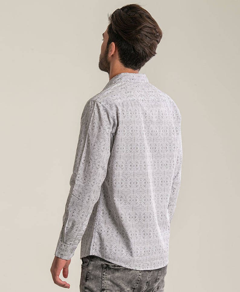 May include: A white long-sleeved shirt with a black geometric pattern. The shirt has a button-down collar and a relaxed fit.