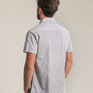 May include: A white short-sleeved button-down shirt with a black geometric pattern.