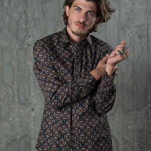 May include: A button-down shirt with a brown and blue floral pattern. The long-sleeved shirt has a classic collar and is made of a lightweight fabric. The shirt is a versatile piece for casual or semi-formal wear.