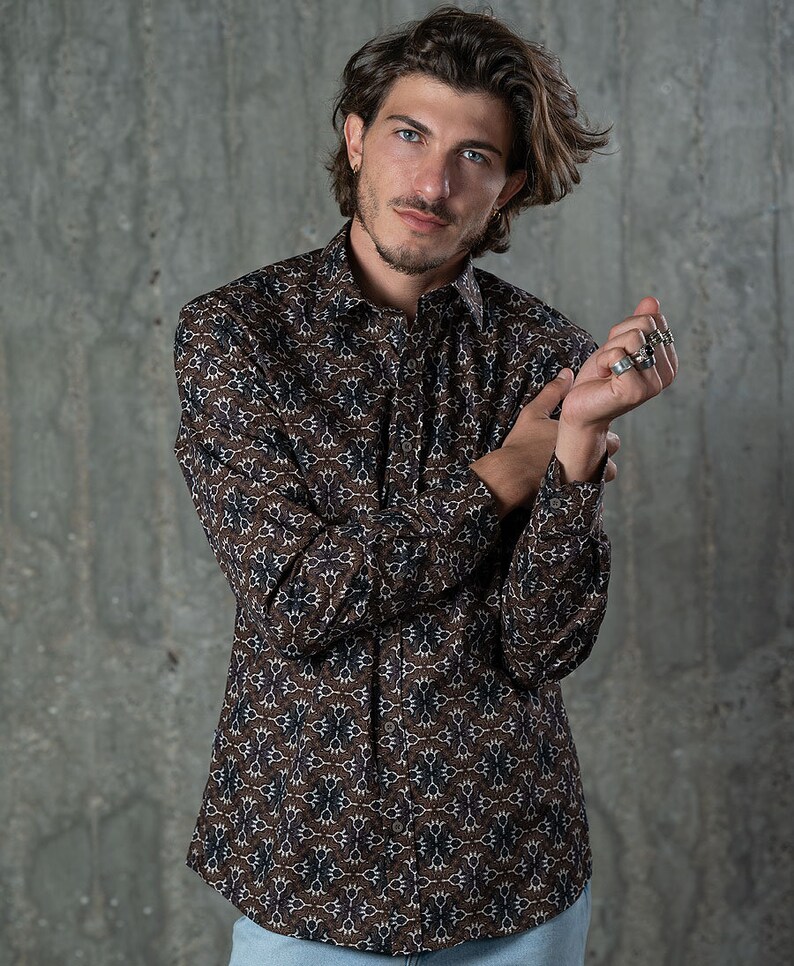 May include: A button-down shirt with a brown and blue floral pattern. The long-sleeved shirt has a classic collar and is made of a lightweight fabric. The shirt is a versatile piece for casual or semi-formal wear.