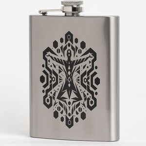 May include: A stainless steel flask with a hinged cap. The flask features a black geometric design on the front. The design is symmetrical and includes various shapes such as hexagons, triangles, and lines. The flask is rectangular with rounded corners.