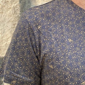 Puede incluir: Una camisa de manga corta azul marino con un patr&oacute;n de panal de abeja dorado y peque&ntilde;as siluetas de abejas.