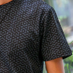 以下が含まれることがあります： 白い幾何学模様が施された黒い半袖Tシャツ。模様は小さな円と線が繰り返されるデザインです。