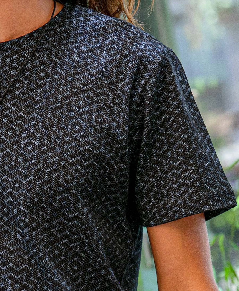 以下が含まれることがあります： 白い幾何学模様が施された黒い半袖Tシャツ。模様は小さな円と線が繰り返されるデザインです。