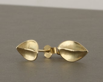 May include: A pair of gold leaf-shaped earrings with a textured surface.