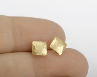 May include: A pair of gold square-shaped earrings with a hammered texture.