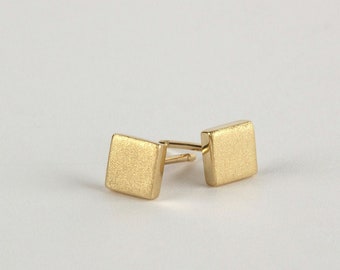 May include: A pair of gold square stud earrings with a brushed finish.
