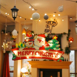 May include: A Christmas decoration featuring Santa Claus, a snowman, and a Christmas tree. The sign reads "MERRY CHRISTMAS" in white letters on a red banner. The decoration is illuminated with warm white lights, creating a cheerful holiday display.