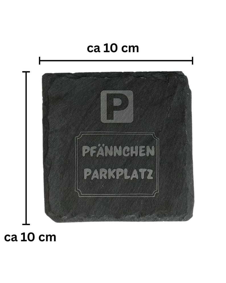 May include: A square, dark gray slate coaster, approximately 4 inches in size, with the letter "P" and the words "PF&Auml;NNCHEN PARKPLATZ" etched into the surface. The coaster has a rough, natural edge.