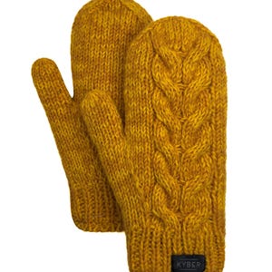 Puede incluir: Un par de manoplas de punto color amarillo mostaza con un patrón de trenzas vertical en la parte delantera. Las manoplas tienen un puño acanalado y una pequeña etiqueta rectangular negra en la parte inferior con el texto blanco KYB&R.