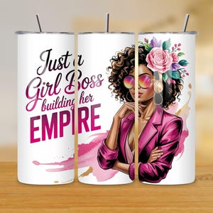 Könnte beinhalten: Ein weißer Becher mit einem Edelstahlstrohhalm zeigt den Text "Just a Girl Boss building her EMPIRE" in Pink und Schwarz. Das Design beinhaltet eine Illustration einer Frau mit Sonnenbrille, einem pinkfarbenen Blazer und einem Blumenschmuck.