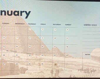 Può includere: Un calendario di gennaio con uno sfondo di paesaggio desertico con piramidi e la Sfinge. La griglia del calendario è impostata su un cielo azzurro chiaro, con il nome del mese in lettere nere in grassetto. Include spazio per obiettivi mensili e note.