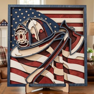 Peut inclure: Une œuvre d'art en bois multicouche représentant un casque et une hache de pompier sur fond de drapeau américain. L'œuvre est encadrée en bleu foncé, avec les étoiles et les rayures du drapeau en rouge, blanc et bleu.