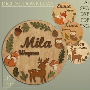 May include: Wooden round name sign with a woodland theme. The sign features a deer, fox, owl, and mushroom design. The name "Mila Wagner" is displayed in brown letters. The sign is 28 cm in diameter.