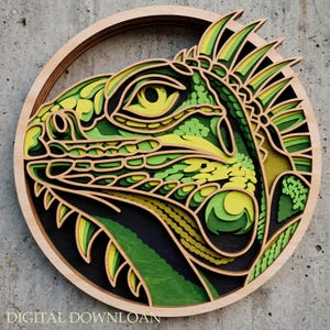 Puede incluir: Una pieza de arte mural circular de madera multicapa que presenta el perfil detallado de una cabeza de iguana. El diseño utiliza tonos verdes, amarillos y negros, con intrincados recortes que crean profundidad. El texto DIGITAL DOWNLOAD es visible.