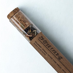 May include: A glass vial with a cork stopper, filled with dried herbs and tea leaves. A brown paper label wraps around the vial, with the Polish text "ŹRÓDŁO ENERGII" and ingredient information.
