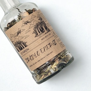 May include: A clear glass bottle filled with loose-leaf tea. The bottle has a brown label with the text "ŹRÓDŁO ENERGII" and an illustration of a waterfall. The label also states "Masa Netto 50g".