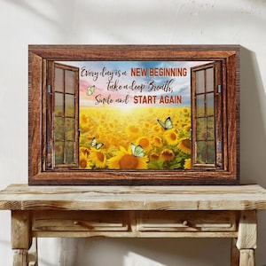 Puede incluir: Una obra de arte enmarcada que representa un campo de girasoles visto a través de una ventana abierta. Se ven mariposas entre los girasoles. El texto en la obra de arte dice: "Every day is a NEW BEGINNING, Take a deep Breath, Smile and START AGAIN."