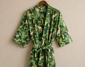 May include: A dark green robe featuring a repeating pattern of leopards and tropical palm leaves. The garment has long sleeves, a shawl collar, and a matching fabric tie belt at the waist, all displayed on a wooden hanger.