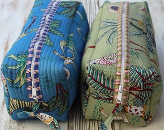 May include: Two rectangular quilted fabric pouches with zippered closures. One pouch is bright blue and the other is sage green. Both feature a repeating tropical print with palm leaves and animal motifs, finished with striped fabric trim along the zipper.