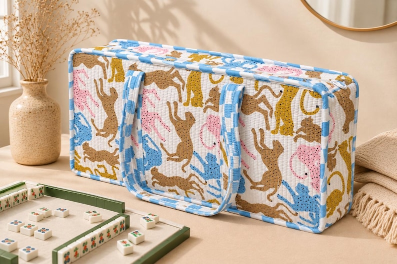 May include: A rectangular quilted fabric storage bag featuring a repeating pattern of stylized leopards in shades of brown, pink, and blue on a white background, finished with a blue and white checkered trim and matching fabric handles.