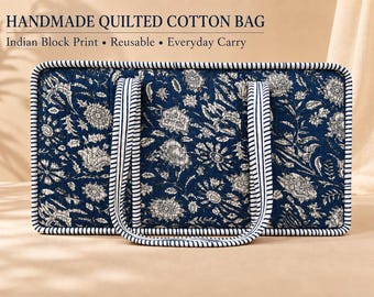 May include: A rectangular quilted cotton bag featuring a dark blue and white floral Indian block print pattern. The bag has two striped handles and matching striped piping along the edges. Text reads: HANDMADE QUILTED COTTON BAG, Indian Block Print, Reusable, Everyday Carry.
