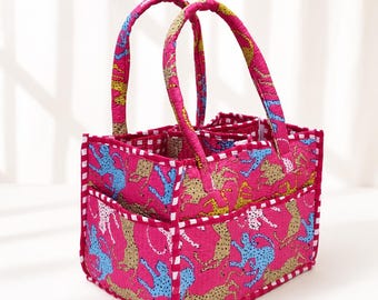 May include: A rectangular quilted fabric storage caddy featuring a vibrant pink base color with a repeating pattern of blue and tan cheetahs. The caddy includes two sturdy fabric handles, an open top, and white and pink checkered trim edges.